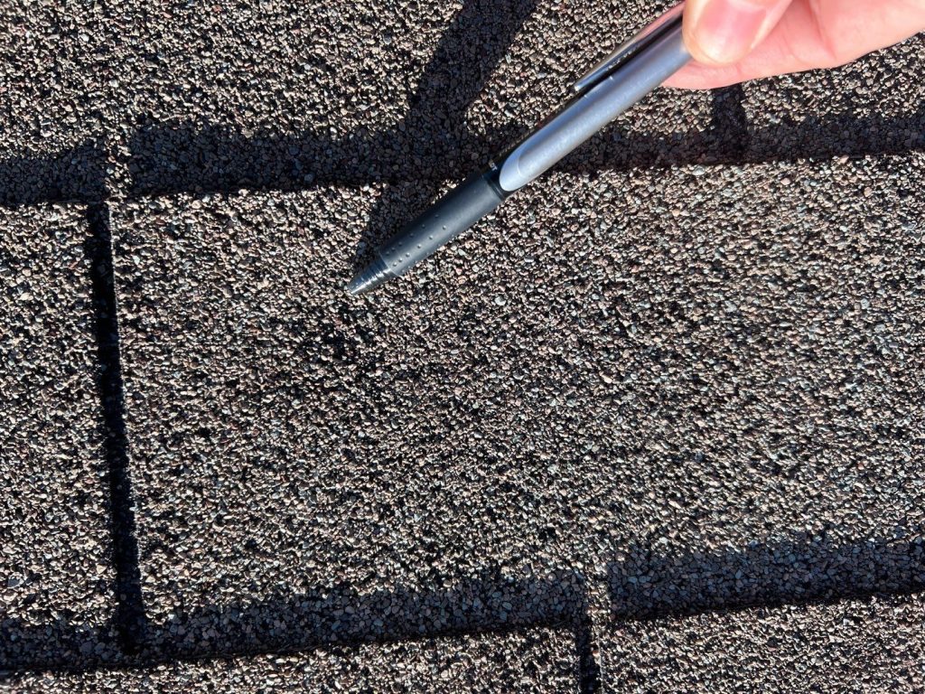 Showing hail damage as it appears on a residential roof shingle.